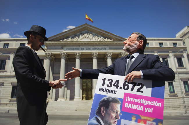 Actors representing the roles of Spanish Prime Minister Mariano Rajoy (right) and a banker pose while staging a flash mob protest against Bankia, outside the Spanish Parliament in Madrid on Tuesday. (AP-Yonhap News)