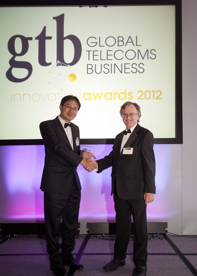 Park Jong-kwan (left), leader of SK Telecom’s core network lab, poses with a GTB official after winning an award at the Global Telecoms Business Innovation Awards in London, Tuesday. (SK Telecom)