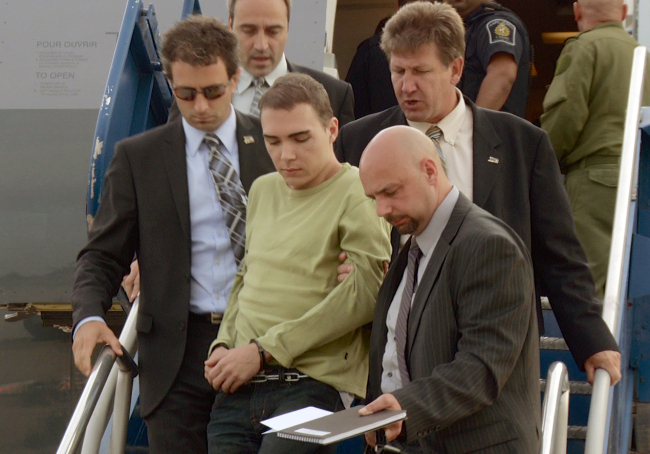 In this photo provided by Montreal Police, Luka Rocco Magnotta is taken by police from a Canadian military plane to a waiting van in Mirabel, Quebec on Monday. (AP-Yonhap News)