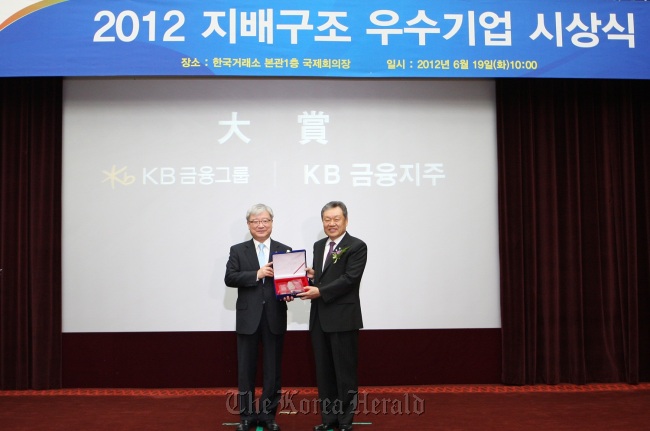 KB Financial Group chairman Euh Yoon-dae (right) poses with Financial Servicies Commission chairman Kim Seok-dong after the lender was named the company with the best corporate governance structure in Korea by the Corporate Governance Service on Tuesday in Seoul. (KB Financial)