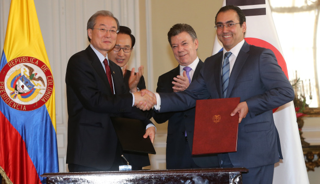 Korean Trade Minister Bark Tae-ho (left) and his Colombian counterpart Sergio Diaz-Granados shake hands after signing a joint statement declaring the end of negotiations in a ceremony in Bogota on Monday attended by Korean President Lee Myung-bak and Colombian President Juan Manuel Santos. (Yonhap News)