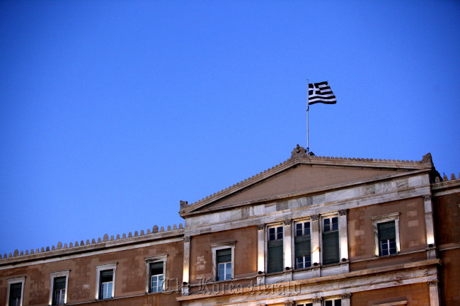 A Greek national flag flies above the parliament building in Athens. (Bloomberg)