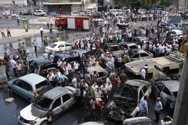 Syrians inspect burned cars at the site of a blast in the Syrian capital Damascus on June 28. (AP-Yonhap News)