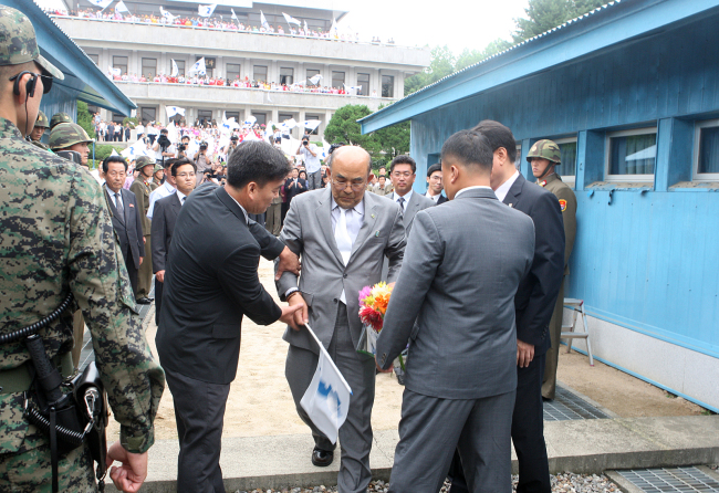 Ro Su-hui (holding a flag), vice chairman of the Pan-Korean Alliance for Reunification, is arrested as he returns to South Korea through the border truce village of Panmunjom on Thursday from his illegal visit to the North. (Ministry of Unification)