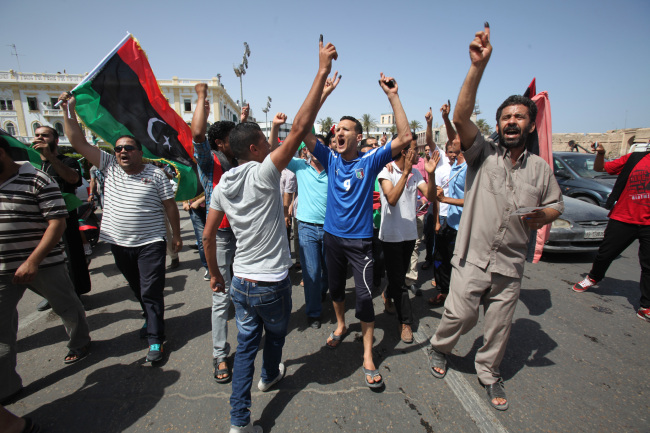 Libyans hold up their ink-marked fingers that shows they have voted as they celebrate in Martyrs’ Square in Tripoli on Saturday. (AP-Yonhap News)