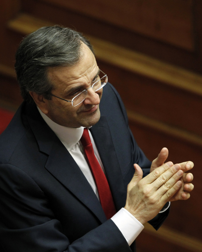 Greek Prime Minister Antonis Samaras applauds at the Parliament after winning a vote of confidence in Athens, late Sunday. (AP-Yonhap News)