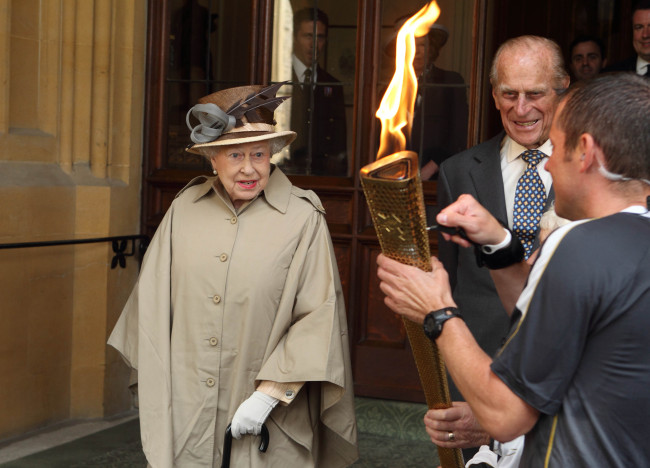 Queen Elizabeth II and Prince Philip look at the Olympic flame on Tuesday. (AP-Yonhap News)