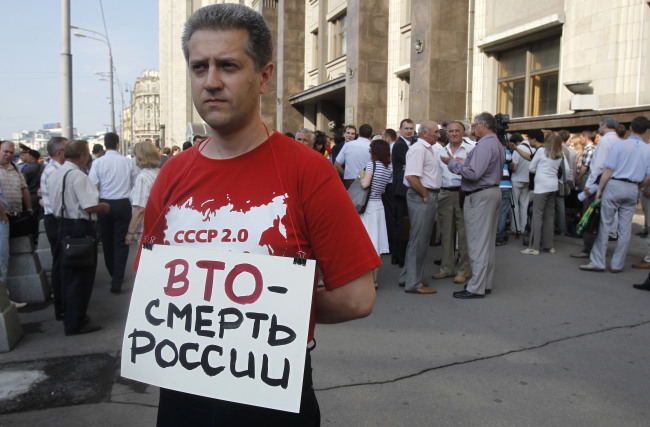 A communist supporter pickets parliament headquarters with a poster reading: “WTO is death for Russia” in Moscow on Tuesday. (AP-Yonhap News)