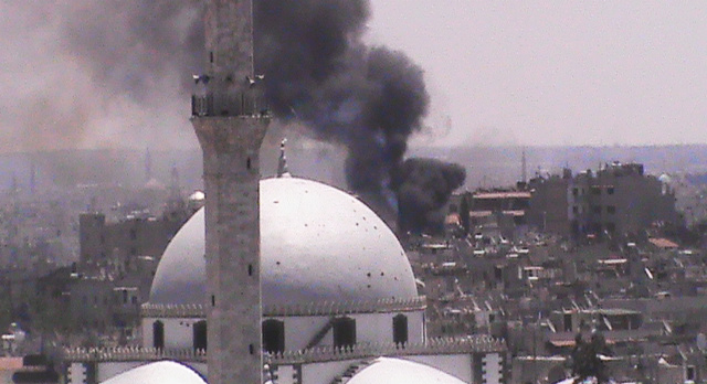 In this citizen journalism image provided by Shaam News Network SNN, taken on Wednesday, black smoke rises from buildings near a mosque from purported forces shelling in Homs, Syria. (AP-Yonhap News)