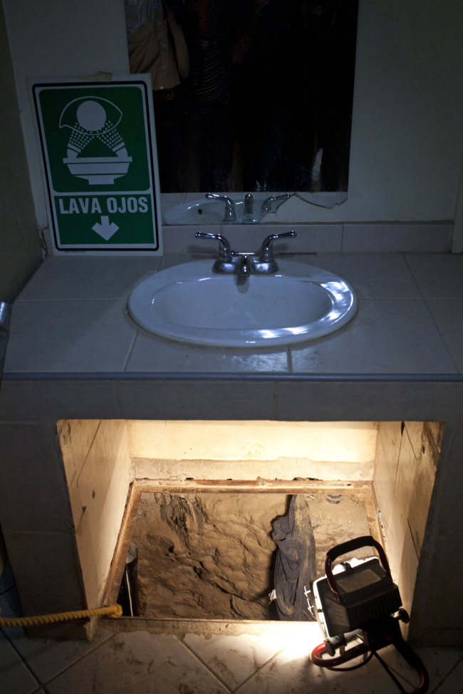 The entrance to a cross border illegal tunnel is lit by a lamp after it was found underneath a bathroom sink by the Mexican army inside a warehouse in Tijuana, Mexico. (AP-Yonhap News)