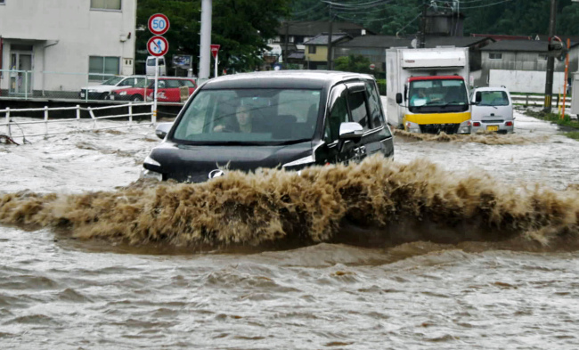 Cars wade through flood water caused by heavy rain in Hita, Oita Prefecture on Saturday. (AP-Yonhap News)