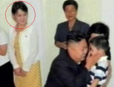 North Korean leader Kim Jong-un (front-center) holds a child during a visit to a Pyongyang kindergarten with an unidentified woman (left) who is speculated to be his wife. (Yonhap News)