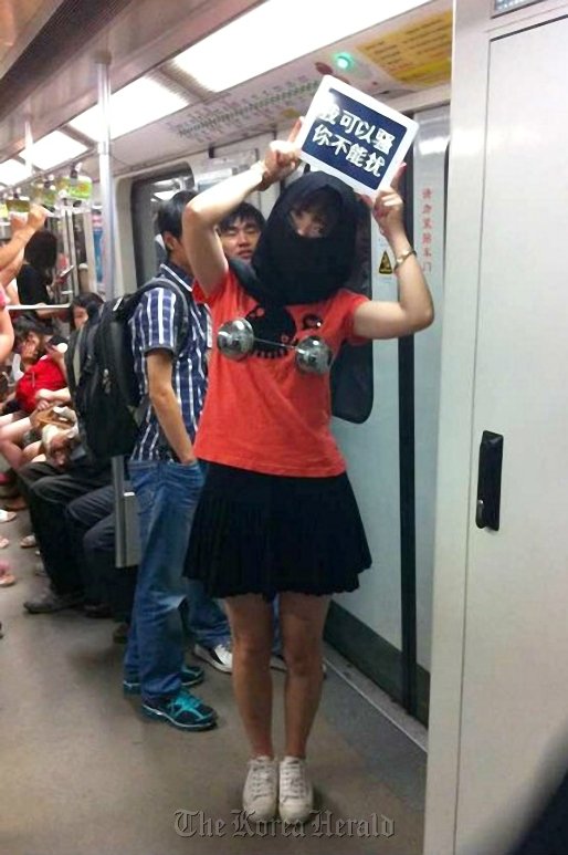 A woman holds a sign reading “I can be coquettish, but you can’t harass me” on Shanghai Metro Line 2.