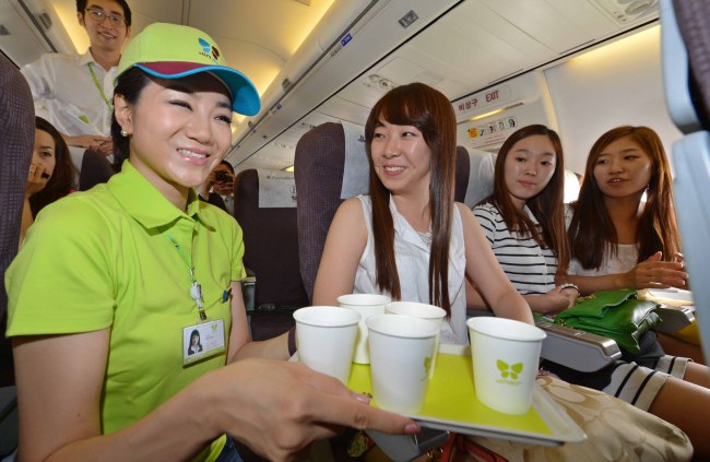 Emily Cho (left), senior vice president of marketing and public relations at Jin Air and the youngest daughter of Korean Air head Cho Yang-ho, serves beverages on a Gimpo-Jeju flight Tuesday. (Yonhap News)