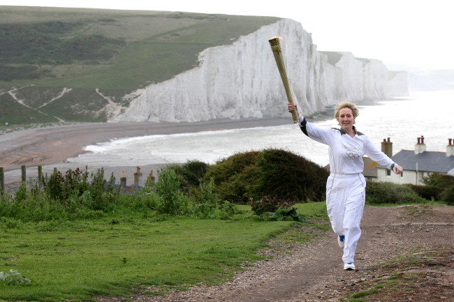 Kathy Gore runs with the Olympic flame in Seaford Head, England, Tuesday. (AP-Yonhap News)