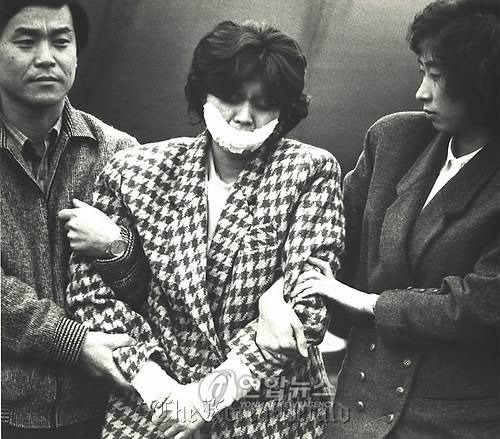 Kim Hyun-hui, a self-confessed North Korean terrorist responsible for the bombing of Korean Air 858, is being transferred under escort at Gimpo International Airport in this file photo taken on Dec. 15, 1987. (Yonhap News)