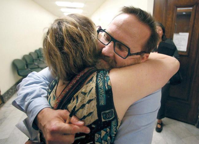 John Brennan (top photo), the man who stripped at Portland International Airport to protest TSA screeners, receives a hug from Amy Baker following his trial in Portland, Oregon, Wednesday. This April 17 file photo (bottom) taken at Portland International Airport shows John E. Brennan standing naked after he stripped down while going through a security screening area, as a protest against airport security procedures. (AP-Yonhap News)