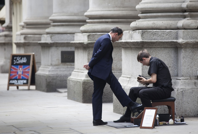 A shoe cleaner polishes the shoes of a businessman outside the Bank of England in London. (Bloomberg)