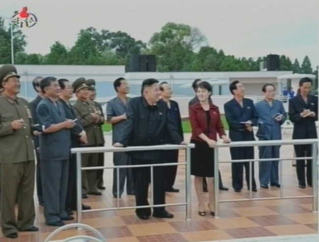 North Korean leader Kim Jong-un is accompanied by the woman speculated to be his wife as he inspects a park in Pyongyang in Korean Central News Agency footage aired on Wednesday. (Yonhap News)