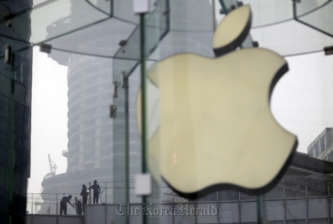 Workers clean the rooftop of a building near an Apple Store that started selling its new iPad tablet computers on July 20 in Shanghai. (AP-Yonhap News)