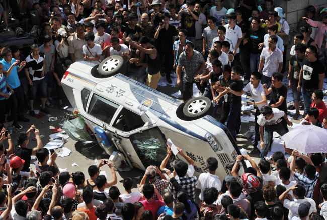 Local residents push over a police vehicle as they gather to protest against plans for a water discharge project in Qidong, China Saturday. (AP-Yonhap News)