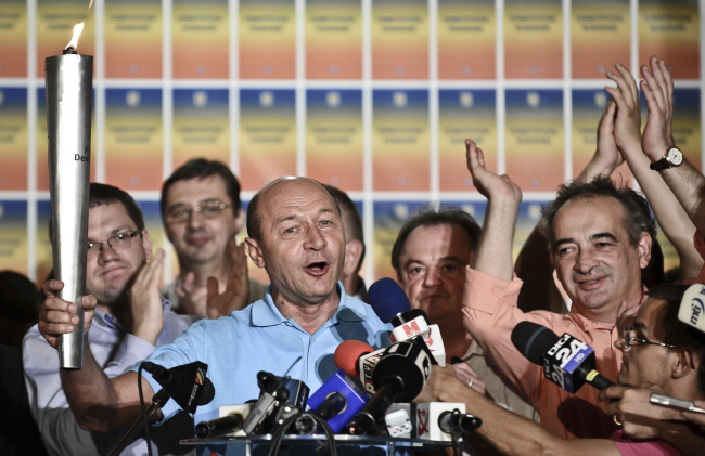 Suspended Romanian President Traian Basescu holds a torch while speaking at the end of the referendum on his possible impeachment in Bucharest on Sunday. (AP-Yonhap News)