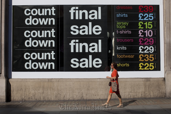 A pedestrian passes a final sale poster advertising discounted goods for sale on Regent Street in London. (Bloomberg)