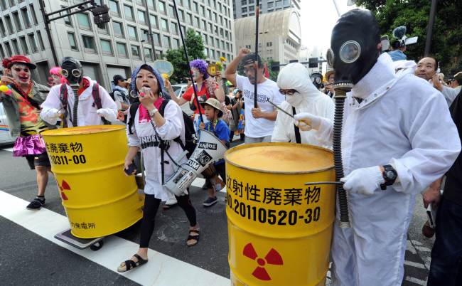 Protesters wearing gas masks and white costumes, similar to those of decontamination workers at the crippled Fukushima plant, beat drums painted with radioactive waste symbols during an anti-nuclear power demonstration in Tokyo on Sunday. (AFP-Yonhap News)