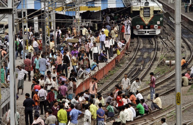 Stranded passengers wait on a platform and some of them on rail tracks for train services to resume following a power outage at Sealdah station in Kolkata, India, Tuesday. (AP-Yonhap News)