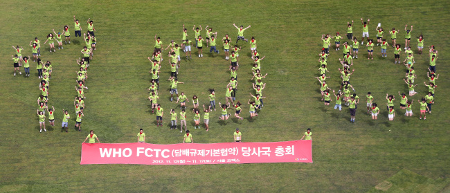 University students participating in anti-smoking campaigns form the number 100 to mark the upcoming World Health Organization Framework Convention on Tobacco Control conference outside the Seoul city hall on Friday. (Yonhap News)