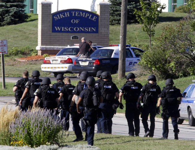 Police walk near the Sikh Temple of Wisconsin in Oak Creek, Wisconsin, after a shooting on Sunday. (AP-Yonhap News)