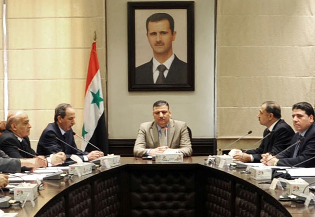 In this undated photo released by the Syrian official news agency SANA on Sunday, Aug. 5, 2012, Syrian Prime Minister Riad Hijab, center, speaks under the portrait of the Syrian President Bashar Assad during a meeting in Damascus, Syria. (AP-Yonhap News)