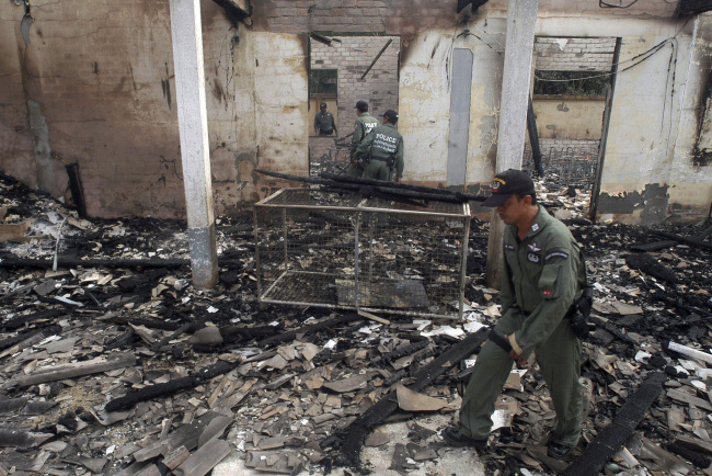 Thai police officers examine the charred Guwing school building after it was burnt down by suspect Muslim separatists in Mayor district of Pattani province, southern Thailand, Aug. 2. (AP-Yonhap News)