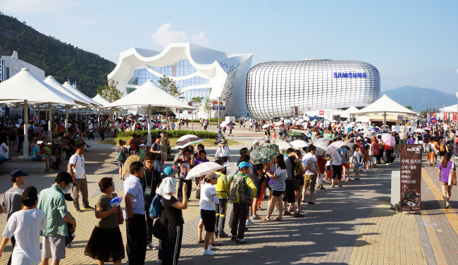 Visitors to the 2012 Yeosu Expo line up in front of a pavilion despite the blistering heat on Tuesday. (Yonhap News)