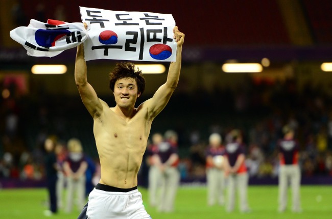 South Korean soccer player Park Jong-woo carries a sign given by a fan that reads “Dokdo Is Our Territory,” after winning the bronze medal match against Japan at the 2012 London Olympics on Friday. The IOC banned him from the medal ceremony for displaying a political message at the match. ( Ahn Hoon/The Korea Herald)