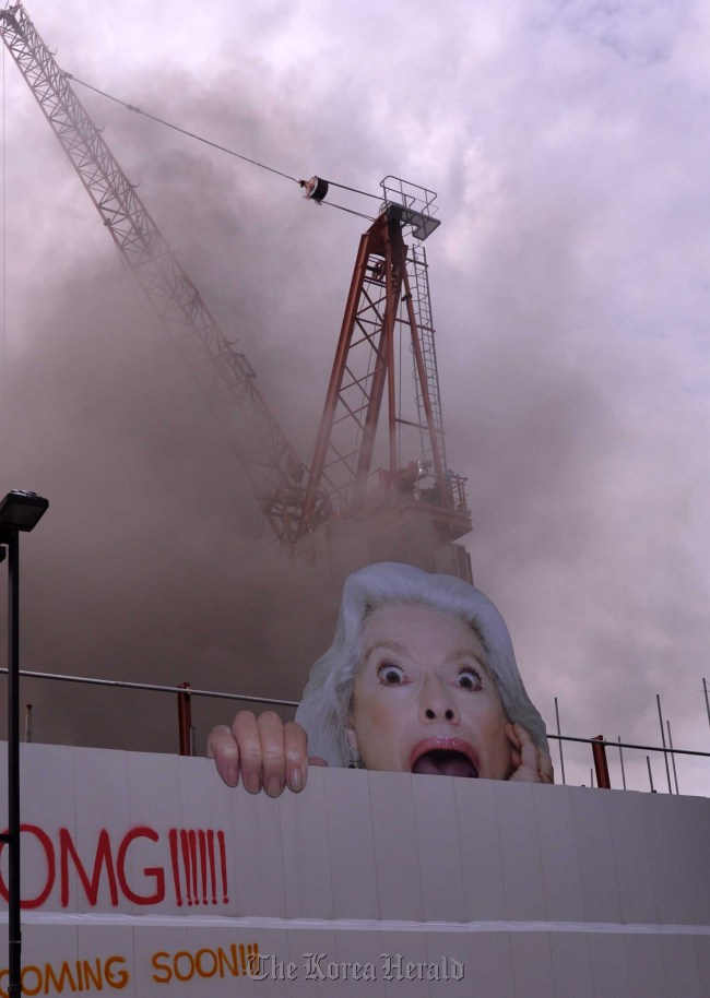 Workers wait to be rescued at the top of a crane after a fire broke out at the construction site for the National Museum of Contemporary Art in Seoul on Monday. (Lee Sang-sub/The Korea Herald)