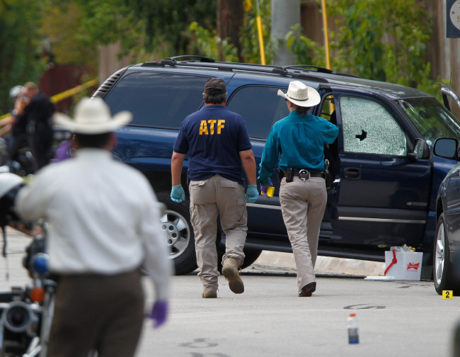 ATF and other investigators walk near a vehicle which was struck by a bullet near the scene where a gunman opened fire near the Texas A&M university in College Station, Texas, Monday. (AP-Yonhap News)