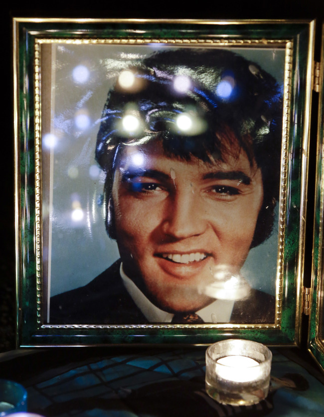 Candles are reflected in a photo of Elvis Presley at a memorial set up by a fan at a candlelight vigil at Graceland, Presley’s Memphis, Tennessee, home, on Wednesday. (AP-Yonhap News)