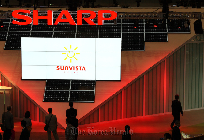 Visitors walk in front of a display of solar panels in the Sharp Corp. booth at CEATEC JAPAN at Makuhari Messe in Chiba City, Japan. (Bloomberg)