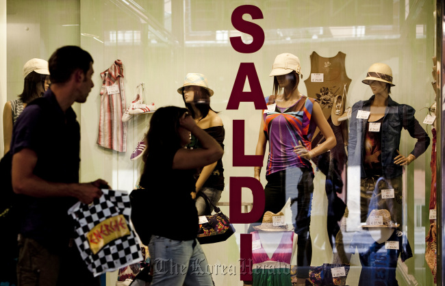 Shoppers pass a store advertising a sale in its window display in Rome. (Bloomberg)