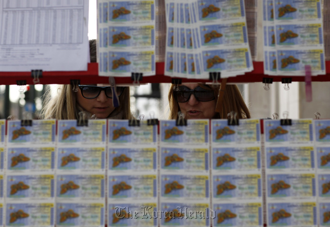 Customers look at state lottery tickets displayed for sale at a street vendor’s stand in Athens. (Bloomberg)