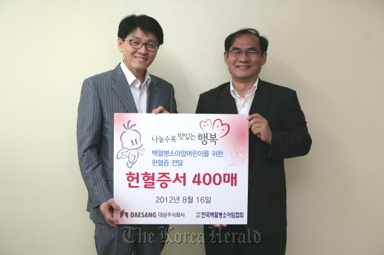 Daesang Holdings executive Joo Hong (left) poses with Chun Jin-wook, secretary-general of the KACLC, after delivering 400 blood donor cards to the association. (Daesang)