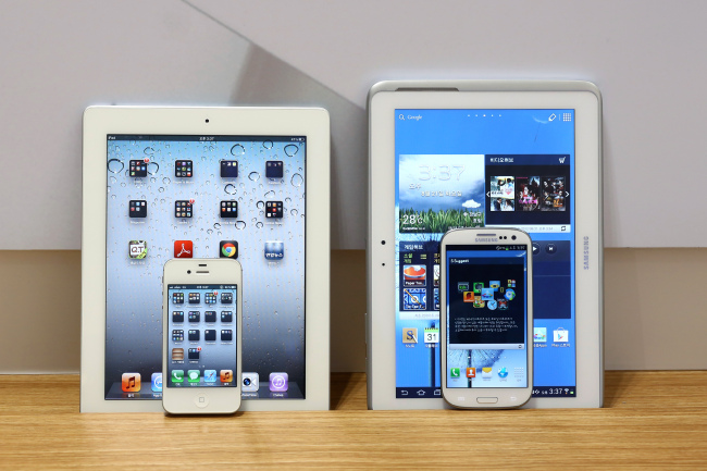 An Apple Inc. iPad 2 and iPhone 4S smartphone, left, and a Samsung Electronics Co. Galaxy Tab 10.1 tablet computer and Galaxy S III smartphone are arranged for a photograph in Seoul, South Korea, On Tuesday. (Bloomberg)