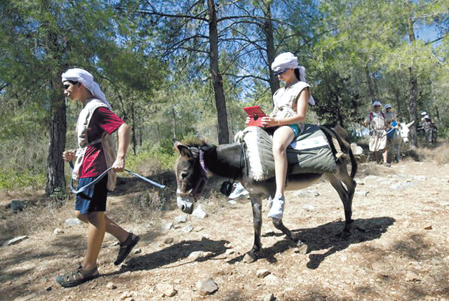 An American tourist uses an iPad while riding a wi-fi-outfitted donkey lead by her brother in Kfar Kedem, a biblical reenactment park in the village of Hoshaya in Galilee, northern Israel, on Wednesday. (AP-Yonhap News)