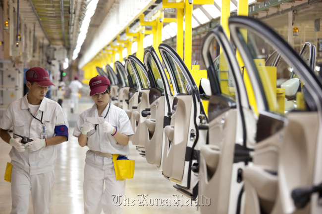 Employees at the Fiat SpA and Guangzhou Automobile Group Co. manufacturing plant walk past door assemblies for Viaggio vehicles in Changsha, Hunan Province, China. (Bloomberg)