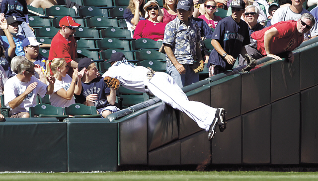 Seattle Mariners left fielder Trayvon Robinson dives into the stands after snagging a foul fly ball from Los Angeles Angels' Maicer Izturis in the fifth inning of a baseball game in Seattle on Sunday. (AP-Yonhap News)
