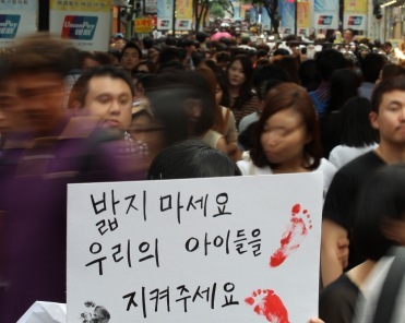 A protestor demanding tougher measures against sex offenders holds a sign that says “Protect our children” in Seoul. (Yonhap News)