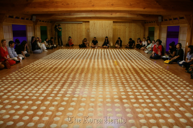 Viewers surround German artist Wolfgang Laib’s “Unlimited Ocean,” which consists of 25,000 piles of rice on a large wooden floor of the Buddhist temple Mugaksa in Gwangju. (Lee Woo-young/The Korea Herald)