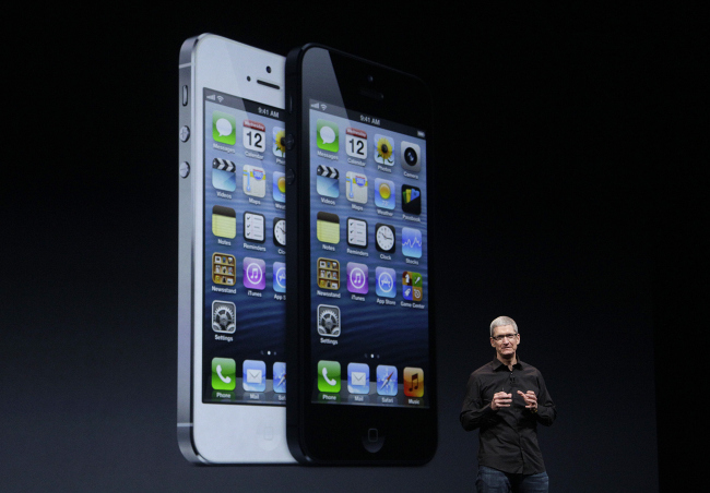 Apple CEO Tim Cook speaks in front of an image of the iPhone 5 during an Apple event in San Francisco, Wednesday. (AP-Yonhap)