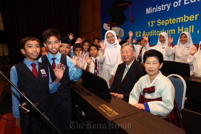 Booyoung Group chairman Lee Joong-keun and his wife Na Kil-soon pose for a photo with schoolchildren Thursday at the Education Ministry auditorium in Putrajaya, Malaysia. (Booyoung)